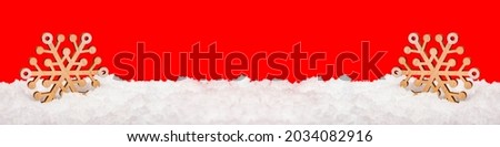 Snow on a red background. Large wooden snowflake in the snow. Christmas concept. New Year theme, panoramic photo for a banner or website header. Christmas card for print or design.