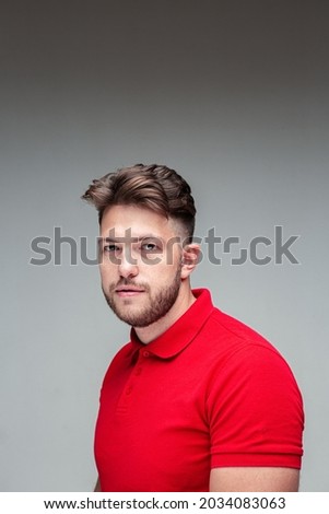 Handsome successful young caucasian bearded guy with stylish haircut, studio portrait on gray background with copy space