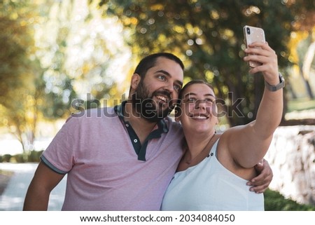 
a chubby couple taking a picture in a park.