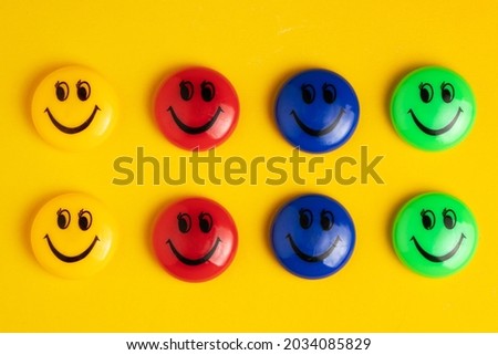 Colorful magnets smile - holders on a yellow background