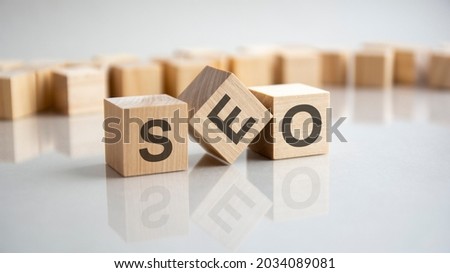 SEO - Search Engines Optimization acronym concept on cubes, gray background. Reflection on the mirrored surface of the table. Selective focus.