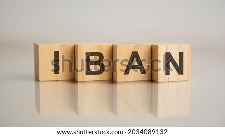 Four wooden cubes with letters IBAN. Business marketing concept. Reflection of the caption on the mirrored gray surface of the table. IBAN short for International Bank Account Number