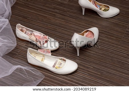 a white wedding shoes full of money and currency. ritual at some weddings-the shoe is filled with money then the bride is given to the groom.