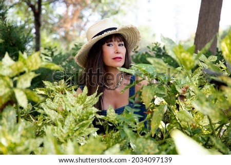 woman poking her head out of green leaves