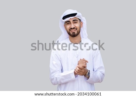 Young handsome Emirati business man in UAE traditional outfit showing a variety of hand gesture. Arabic ambitious mature businessman. Royalty-Free Stock Photo #2034100061