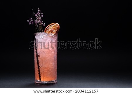 luxury lemonade drink or pink cocktail with ice in glass on black background
