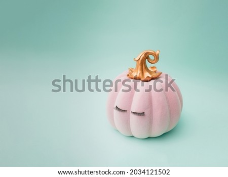 Pink Halloween fairy tale pumpkin with golden petiole and eyelashes. Green mint background color. Minimal design.