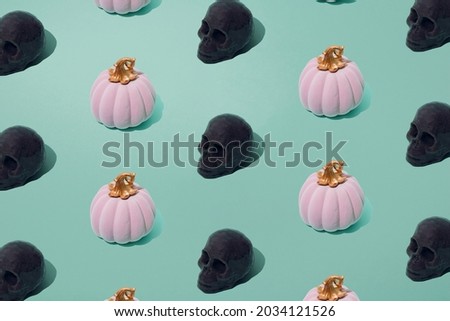 Arranged pink Halloween fairy tale pumpkin with gray skull on mint seafoam pastel background. Minimal design and pattern.