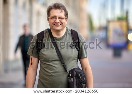 Middle aged man with cross body bag and backpack outdoors. Royalty-Free Stock Photo #2034126650