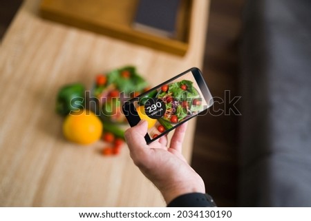 Close up of a person taking a picture with a smartphone of his green and vegetables to use a calorie counting app 