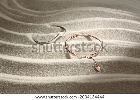 woman jewelry bracelet on white sand with moody sunset lighting