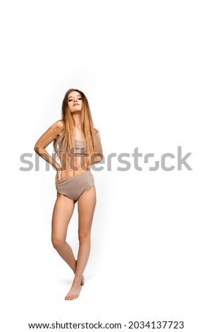 Young, fit and beautiful slender girl in gray sports underwear posing on a white background. Health care, diet, sport and fitness concept