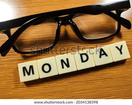Business concept.Selective focus.Glasses and Scrabble letters with text MONDAY on wooden background.