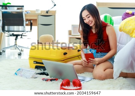 Young happy and excite Asian female traveler getting ready for a summer holiday trip vacation making notes on travel information and using laptop in bedroom.