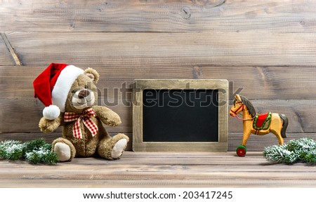 nostalgic christmas decoration with antique toys teddy bear and wooden rocking horse. vintage style picture with blackboard for your text