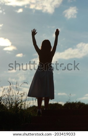 Silhouette of of a little girl on nature background at sunset