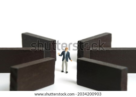 Miniature people toy figure photography. Strategy choice concept. A shrugging businessman standing in the middle of wooden maze labyrinth. Isolated on white background. Image photo