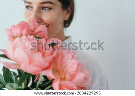 Happy woman smelling a bouquet of coral sunset peony