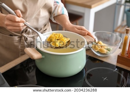Woman cooking tasty ravioli in kitchen Royalty-Free Stock Photo #2034236288