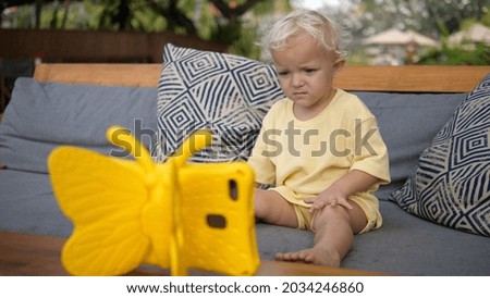 Toddler child watching a cartoon on a digital tabled in a kid -riendly yellow butterfly case