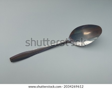 a spoon made of stainless with a gray background