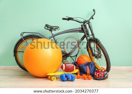 Set of sport equipment with bicycle near color wall