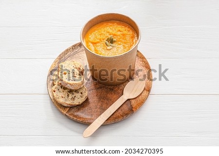 Tasty pumpkin cream soup in cup on table