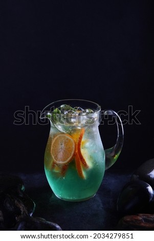 Classic non-alcoholic Mojito lemonade. Homemade cold lemonade. Fresh fruits in a glass jug. Black background. Vertical photo. Copy space.