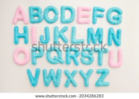 Full alphabet in  capital letters made from stuffed felt on isolated milky white background. Games of learning. Montessori colors.