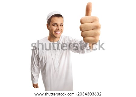 Young cheerful man in white ethnic clothes showing thumbs up in front of camera isolated on white background