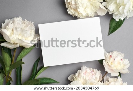 Greeting or invitation card mockup with copy space and white peony flowers on grey background Royalty-Free Stock Photo #2034304769