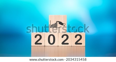 Wooden cube with concept of business progress in new year 2022 on blue background