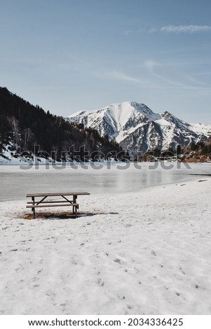 Frozen lake with a picnic table and snowy mountain views in France