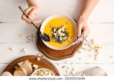 Woman eating tasty popcorn soup from bowl