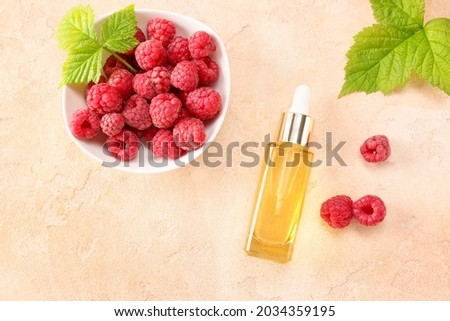 Bottle of raspberry essential oil on color background