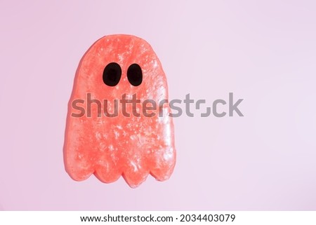 Pink slime ghost with black eyes against pink background.