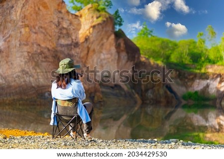 A female tourist sits taking pictures of the beautiful mountain scenery in the afternoon.