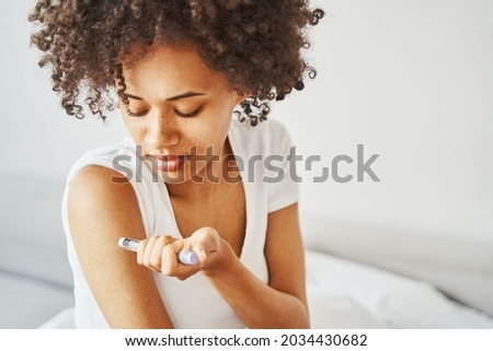 Female diabetic injecting insulin into her upper arm Royalty-Free Stock Photo #2034430682