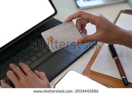 Close up female using computer tablet and holding credit card for banking online.