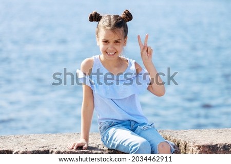 beautiful young girl shows a sign of victory and smiles. High quality photo