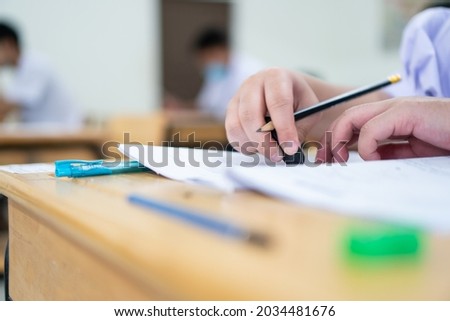 Asian Student using rubber eraser in writing learning Exams in classroom. at high school of education. School student's read note taking assessment writing on answer papers for asmission in classmates Royalty-Free Stock Photo #2034481676