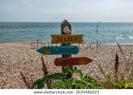 fun sign on the beach at  Selsey West Sussex England pointing to the sunrise and sunset