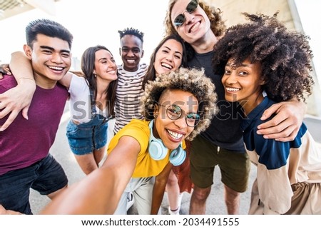 Multicultural happy friends having fun taking group selfie portrait on city street - Multiracial young people celebrating laughing together outdoors - Happy lifestyle concept	