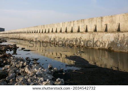 A sea wall made of concrete to prevent water comes inside the inner land due to sea level rise. Translation: "BASE means base.", "STA 2150, 12 150, 708 have no common meanings. Only scratch." Royalty-Free Stock Photo #2034542732