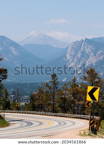 Winding road to the mountains with left turning sign. 