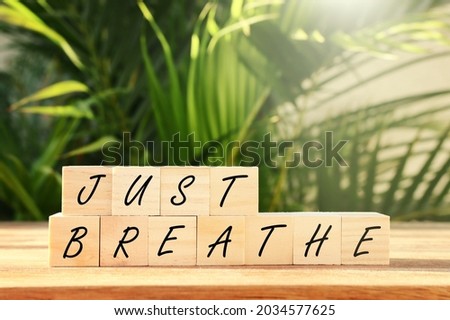 Wooden blocks with the text Breathe over green floral background