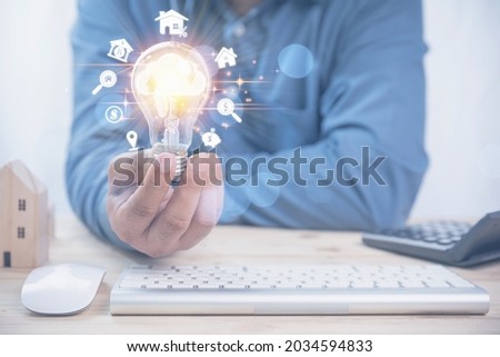 Businessman holding lighting bulb with cloud icon, business icon. Idea saves money for investment real estate, residential. Use technology cloud system.
