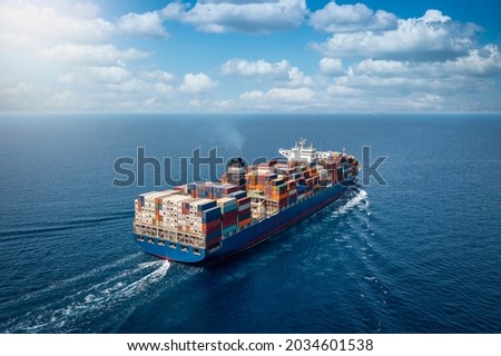 A large container cargo ship travels over calm, blue ocean Royalty-Free Stock Photo #2034601538
