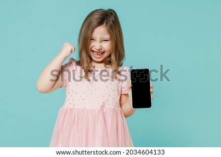 Little fun cute kid girl 5-6 years old wears pink dress hold in hand using mobile cell phone isolated on pastel blue color background child studio portrait. Mother's Day love family lifestyle concept