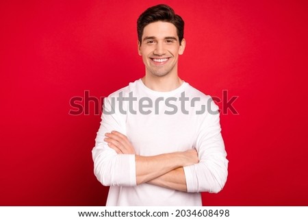 Photo portrait brunet guy in white shirt confident smiling crossed hands isolated vivid red color background